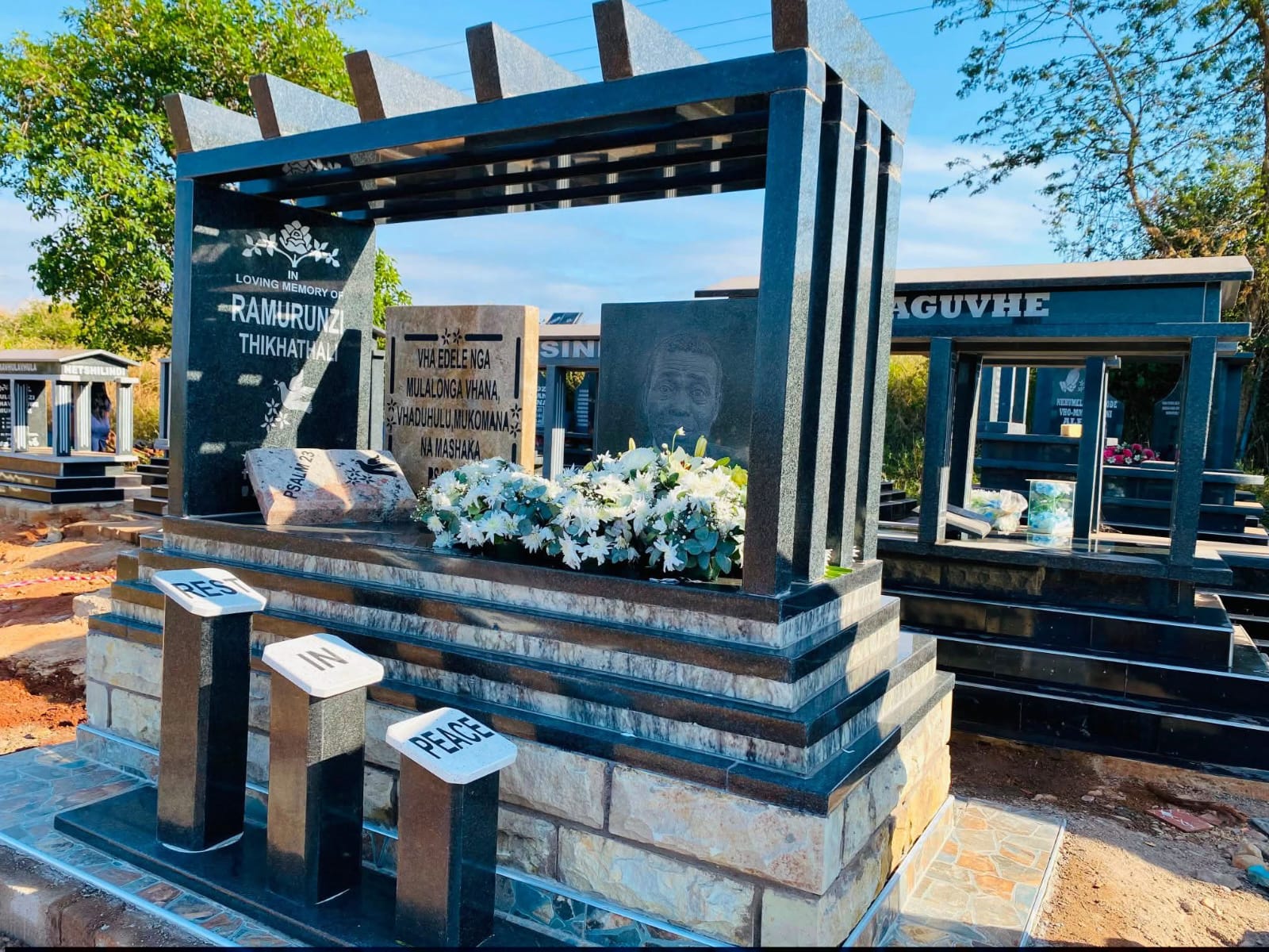 Completed granite memorial with engraved panels, flowers and a tiled base